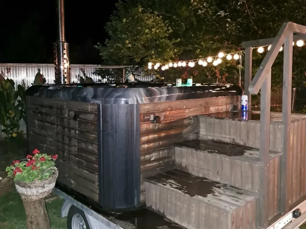 Esti dézsafürdő lépcsővel, fényfüzér alatt a kertben